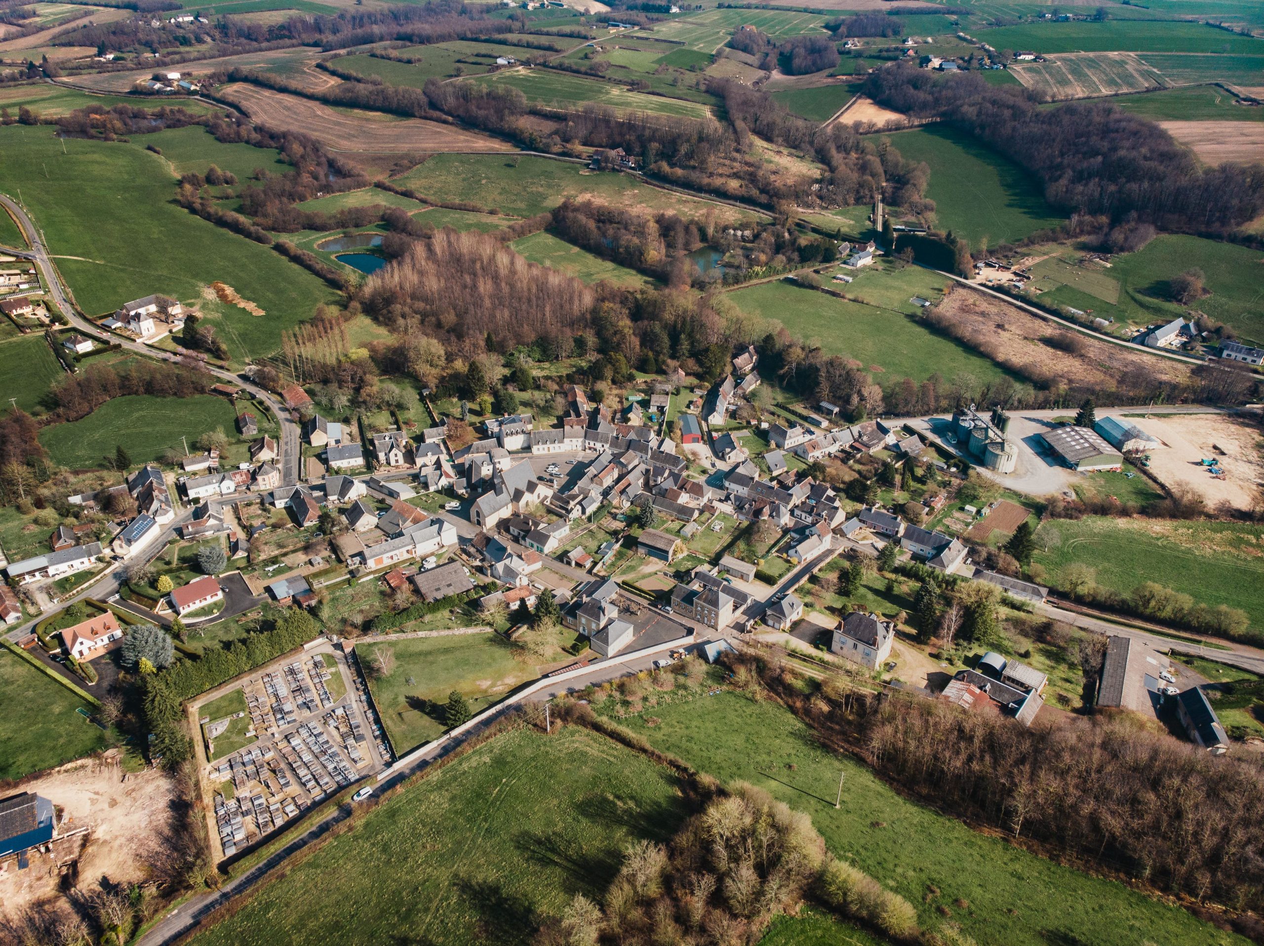Explore the charming village of Vancé, France, from above, surrounded by lush landscapes.